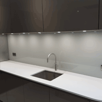 a coloured splashback behind a sink run in a kitchen
