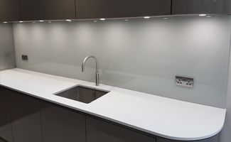 a coloured glass splashback installed behind a sink run